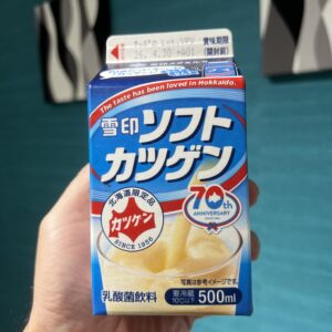 北海道限定の乳酸菌飲料「雪印ソフトカツゲン」の500mlパック。背景のターコイズブルーの壁に、青いパッケージが鮮やかに映える一枚。