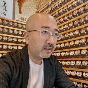 鑑定に真剣に向き合う石屋蓮店主・蓮水雲州。知的な視線で石の性質を読み解く姿。