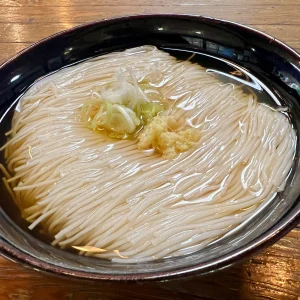 大岩そうめんのクローズアップ。器の中で一筋の乱れもなく綺麗に整えられた、流れる髪のように美しい麺線。中央には生姜と刻みネギがちょこんと添えられ、清らかな出汁に浸っている。