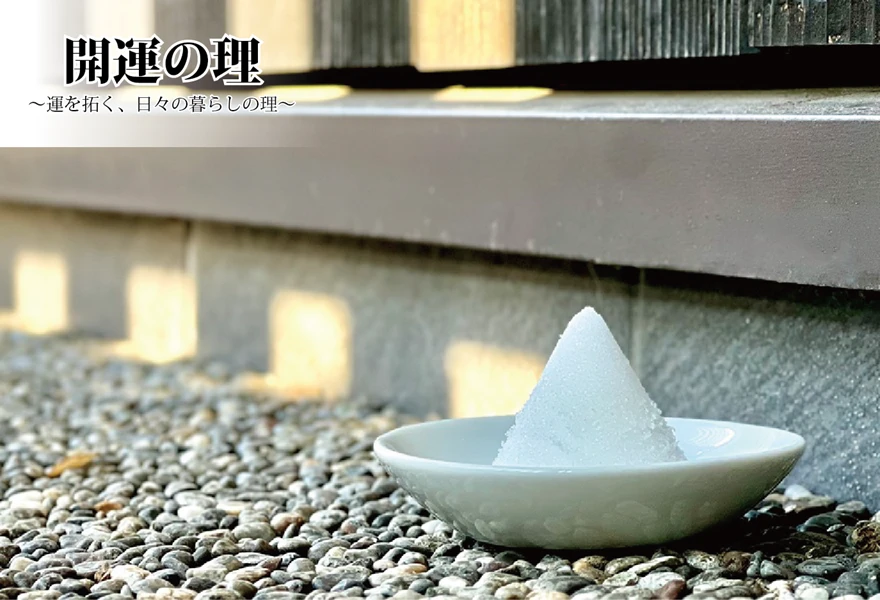 石屋蓮本店「瑞照庵」の玄関先。玉砂利が敷き詰められた足元に、白い小皿に美しく円錐状に盛られた盛り塩が置かれており、背景の壁には柔らかな日差しが差し込んでいます。左上には「開運の理 〜運を拓く、日々の暮らしの理〜」という文字が配置されています。