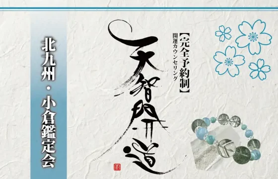 明るいオフホワイトの手漉き和紙を背景に、中央に大きく「天智開道」と力強い筆文字を配した鑑定会告知画像。左側には水色のグラデーションがかかった垂直の帯があり、その上に「北九州・小倉鑑定会」と白い影付きの文字が凛と並んでいる。右上の余白には青い線画の桜が舞い、右下には水晶と淡い水色の天然石を組み合わせたブレスレットが置かれている。筆文字の右隣には「【完全予約制】開運カウンセリング」と黒い縦書き文字が添えられ、全体として清潔感と品格が漂う和のデザイン。