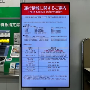 台風6号の接近に伴い、多くの路線が運休や運転見合わせとなっていることを知らせる電子掲示板。刻々と変わる運行状況が冷たく表示されており、嵐の到来を告げている。