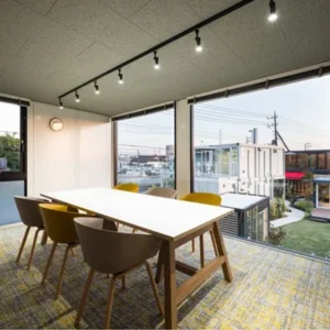 石屋蓮 茨城・ひたちなか鑑定会会場の室内風景。天井に走るライティングレールがモダンな空間を演出し、開放的な大きな窓からは空と街の景色が広がります。中央にはゆったりとしたテーブルと色鮮やかな椅子が配され、訪れる方の心を解きほぐすような明るい雰囲気に満ちています。鑑定という特別なひとときを、晴れやかな気持ちで迎え入れられる、広がりと安らぎを感じる場所です。