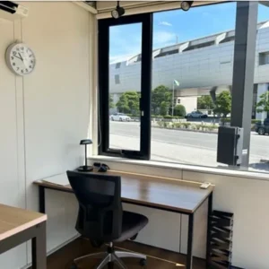 石屋蓮 松山鑑定会会場の室内風景。白を基調とした壁面に大きな窓が広がる、開放感のある個室空間です。窓の外には通りと緑、空が眺められ、室内にはすっきりと整えられたデスクと椅子が置かれています。外の景色を取り込みながら、ご自身の心と深く向き合うための、静寂の中に確かな温もりを感じさせる鑑定場所です。