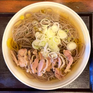 真上から捉えた、特盛の山形肉そば。透き通ったスープの表面に鶏の脂が光り、中心には白ネギ、親鶏の肉が鮮やかに添えられています。